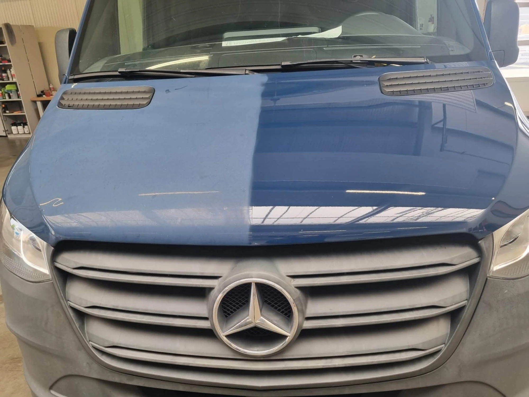 Motorhaube eines blauen Mercedes Sprinter: linke Hälfte unbehandelt und matt, rechte Hälfte poliert und glänzend